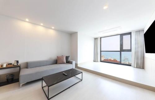 a living room with a couch and a large window at Geoje Mongdol Beach H Avenue Hotel in Geoje 