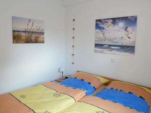 ein Schlafzimmer mit einem Bett und zwei Bildern an der Wand in der Unterkunft Heubude in Greetsiel