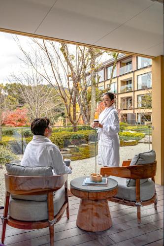 a woman standing next to a man sitting in a chair at Four Seasons Hotel Kyoto in Kyoto