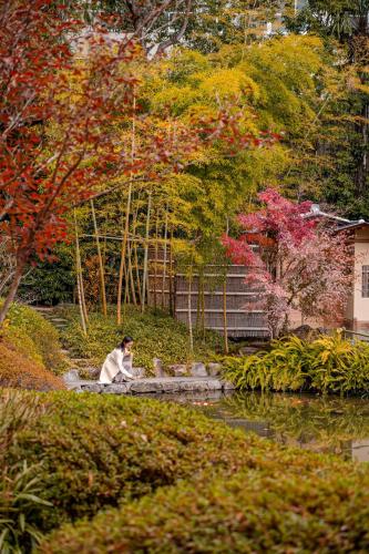 a woman sitting in a garden next to a pond at Four Seasons Hotel Kyoto in Kyoto