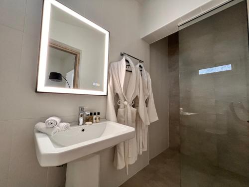 a bathroom with a sink and a mirror and a shower at Perla Coco Jacuzzi Suites in Chania Town