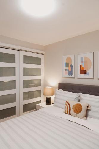 a white bedroom with a large white bed and a lamp at Modern, Luxurious Apartment near Downtown Ottawa in Ottawa