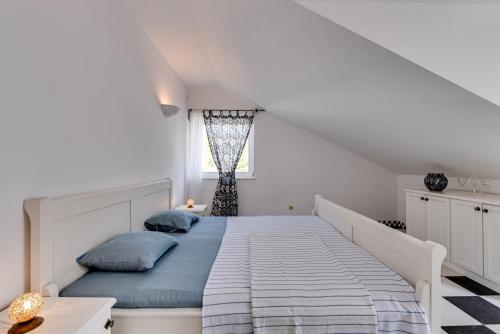 Dormitorio blanco con cama con almohadas azules en Seaside house with a swimming pool Pasadur, Lastovo - 15847, en Lastovo