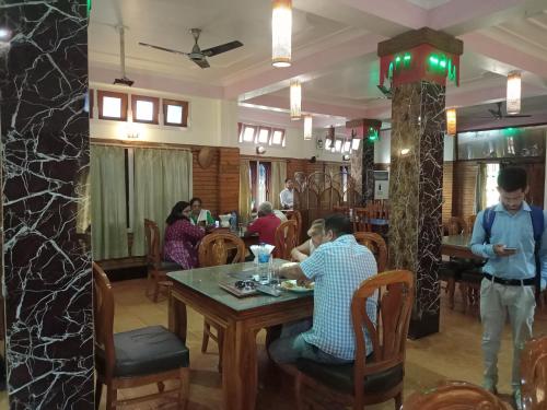 um grupo de pessoas sentadas à mesa de um restaurante em Dichang Resorts em Guwahati