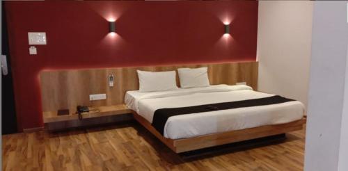 - une chambre avec un grand lit et un mur rouge dans l'établissement TGN SUITES - HOTEL, à Raipur