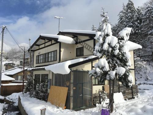una casa cubierta de nieve con un árbol en Matsuo House - Max 4 person Room Aki en Zao Onsen