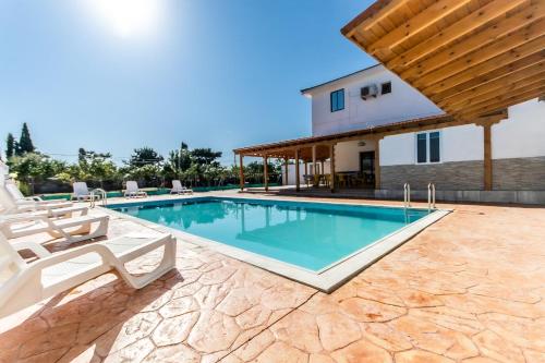 a swimming pool with chairs and a house at Reel Paradise Villa, Cyprus in Larnaka