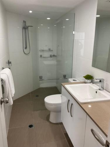 a white bathroom with a toilet and a sink at Broadbeach Holiday Apartments in Gold Coast