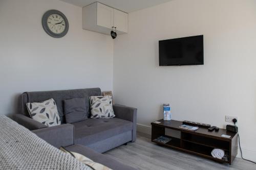 a living room with a couch and a tv at Hegarty's cottage at Trevarrian Lodge in Mawgan Porth
