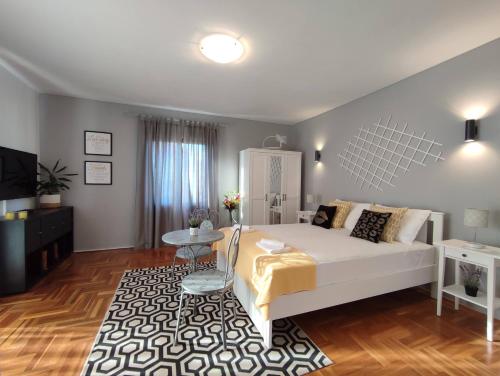 a bedroom with a large white bed and a table at Apartments with a swimming pool Razanj, Rogoznica - 16182 in Rogoznica