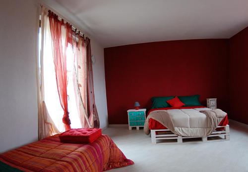 a bedroom with red walls and a bed and a window at Bed and Breakfast Ca D'Pandin in Peveragno