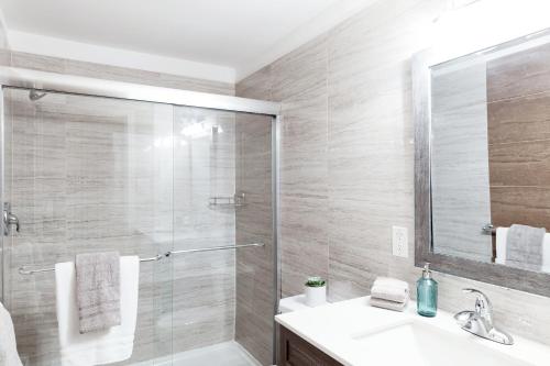 a bathroom with a shower and a sink and a mirror at Modern, Luxurious Apartment near Downtown Ottawa in Ottawa