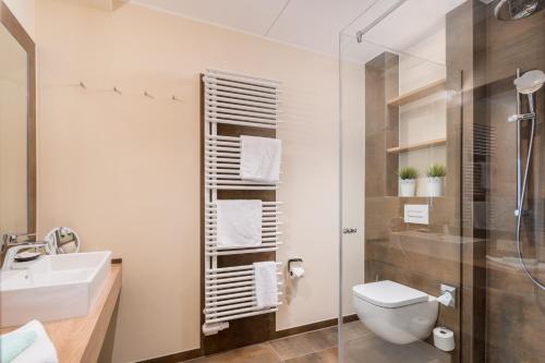 a bathroom with a toilet and a sink and a shower at Parkhotel Jever in Jever