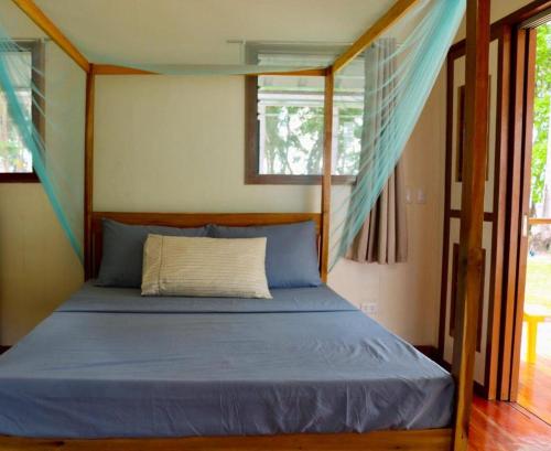 a bedroom with a bed with blue sheets and a window at Mariejoy Haven Beach Resort in San Vicente