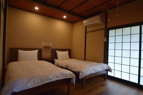 two beds in a room with a window at MY LODGE Naoshima in Naoshima