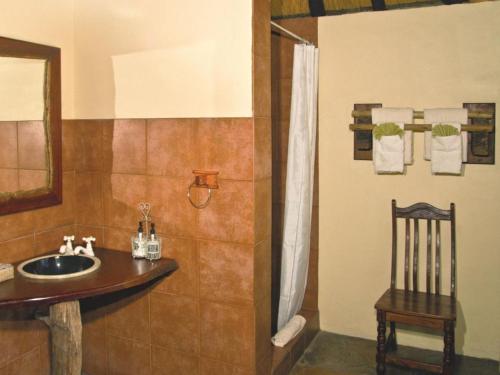 a bathroom with a sink and a shower with a chair at Lianshulu BUSH Lodge in Kongola