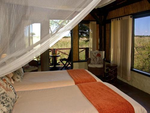Kongola的住宿－Lianshulu BUSH Lodge，一间卧室配有一张床,享有田野美景