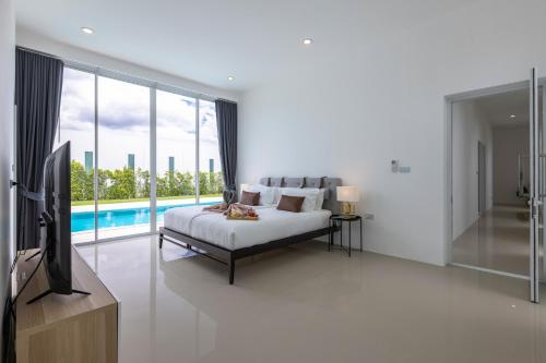 a bedroom with a bed and a tv and a pool at Modern 4 Bedroom Pool Villa KH-A6 in Khao Tao