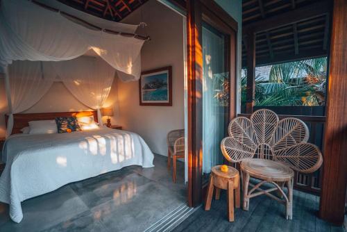 a bedroom with a bed and two chairs and a window at Melali Bingin in Uluwatu