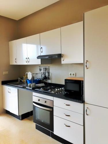 a kitchen with white cabinets and a black stove top oven at Superbe appartement en bord de mer in Kenitra