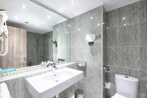 a bathroom with a sink and a toilet and a mirror at Mercure Luxembourg Kikuoka Golf & Spa in Canach