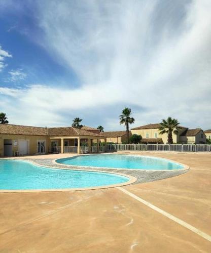 une grande piscine devant un immeuble dans l'établissement La Maisonnette des Berges, à Béziers