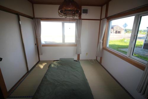 um pequeno quarto com uma cama e duas janelas em 海と湖が近い一軒家　”民泊あばしりの家” 