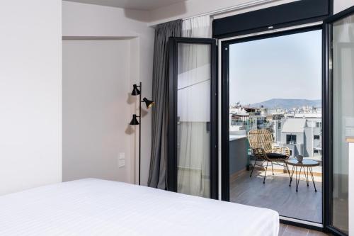 1 dormitorio con cama y vistas a un balcón en Empress Luxury Residences, en Volos