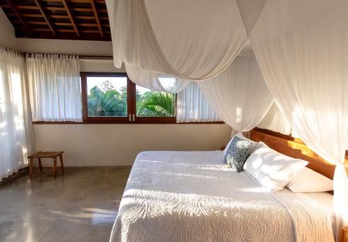 a bedroom with a bed with white drapes at Melali Bingin in Uluwatu