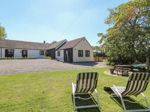two chairs sitting in the grass in front of a house at The Den, Bank Top Farm in Ashbourne