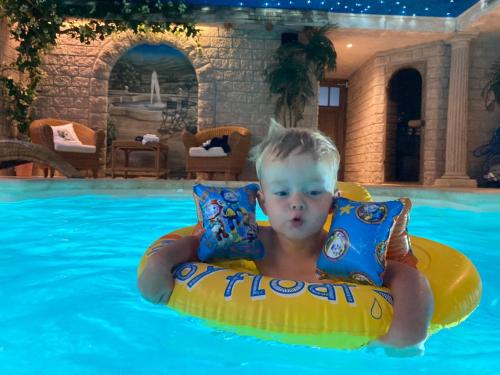 a young boy in a raft in a swimming pool at B&B. Het Hunebed Rolde in Rolde