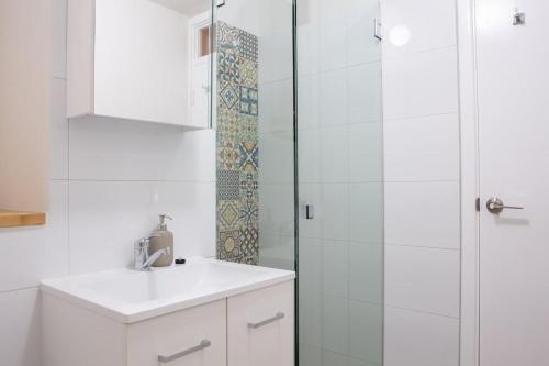 a white bathroom with a sink and a shower at Central Fremantle Lifestyle Walk To Markets & Cafe in Fremantle
