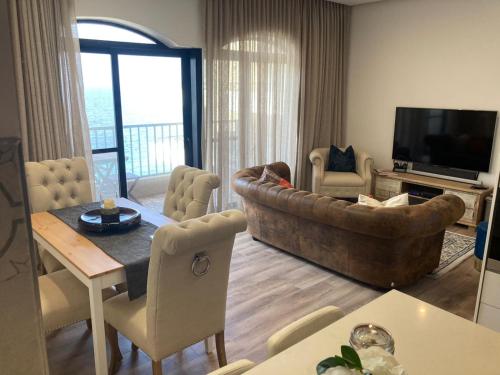 uma sala de estar com um sofá e uma televisão em Beach front High End apartment, direct sea views. em Marsalforn