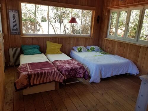 2 camas en una habitación con ventanas en les cabanes, en Lège-Cap-Ferret