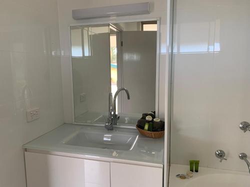 ein weißes Badezimmer mit einem Waschbecken und einem Spiegel in der Unterkunft Orbost Country Man Motor Inn in Orbost