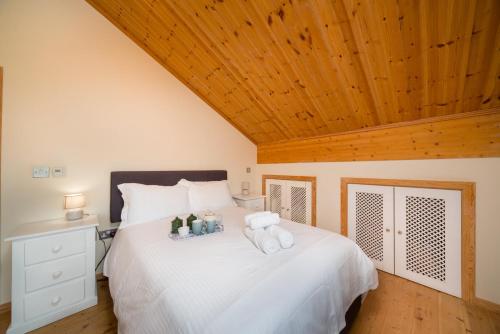 Un dormitorio con una cama blanca con dos animales de peluche. en Finest Retreats - Puddleduck, en Fritton