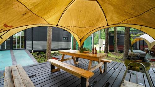 um deque de madeira com uma mesa e uma tenda em 森と湖の楽園ＷorkshopＣampＲesort em Fujikawaguchiko