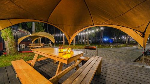 a picnic table and benches under a large tent at 森と湖の楽園ＷorkshopＣampＲesort in Fujikawaguchiko