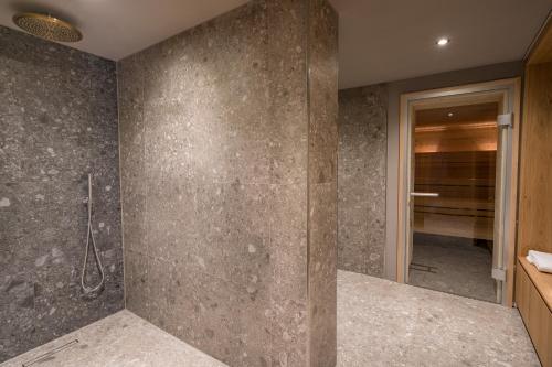 a bathroom with a stone wall with a shower at Goldbrunn in Oberstdorf