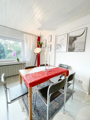 a dining room with a red table and chairs at Ginius Homes - Eifelglück im Grünen in Kall