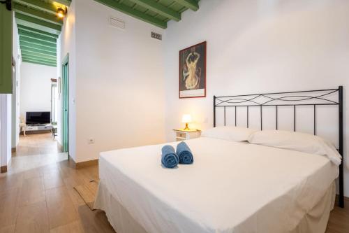 een slaapkamer met een wit bed met blauwe schoenen erop bij Charming apartment at La Alameda Seville City Center by Oui Sevilla in Sevilla
