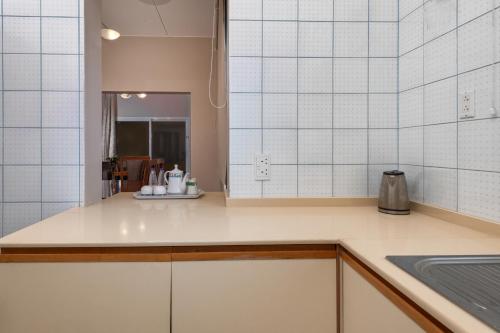 uma cozinha com paredes de azulejos brancos e uma bancada em Airport Hotel and Resort em Abha