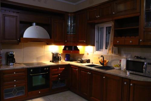 a kitchen with wooden cabinets and a stove top oven at VILLA DIAMOND Κουρούτα Αμαλιαδος in Amaliás