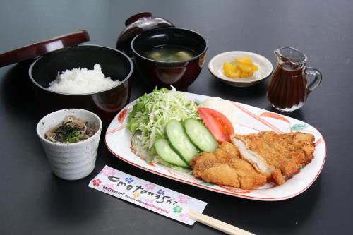 a table with a plate of chicken and vegetables and rice at Business Hotel Furusato in Ibusuki