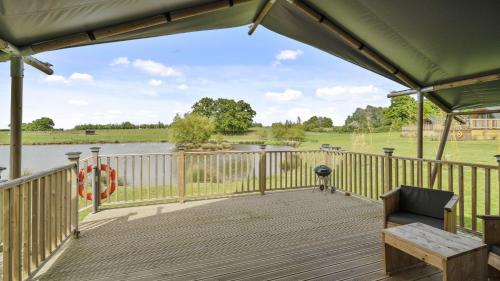 a large deck with a view of a lake at The Herdwick Safari Tent in Hertford