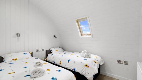 two beds in a room with white walls and a window at Finest Retreats - The Chicken Coop in Hertford