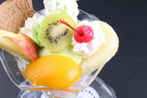 a fruit salad in a glass bowl with a banana and an orange at Business Hotel Furusato in Ibusuki