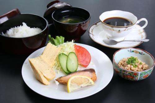 a table with a plate of food and a cup of tea at Business Hotel Furusato in Ibusuki
