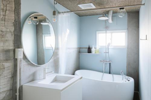 een badkamer met een witte wastafel en een spiegel bij RE SORT in Sasebo