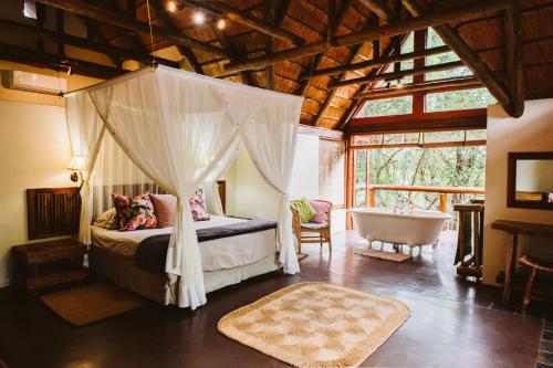 a bedroom with a canopy bed and a bath tub at Hluhluwe River Lodge in Hluhluwe